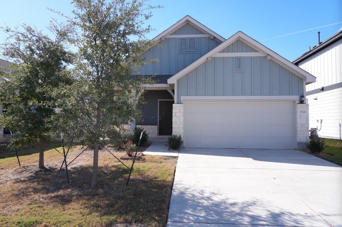 Craftsman inspired home featuring board and batten siding, driveway, a garage, and stone siding