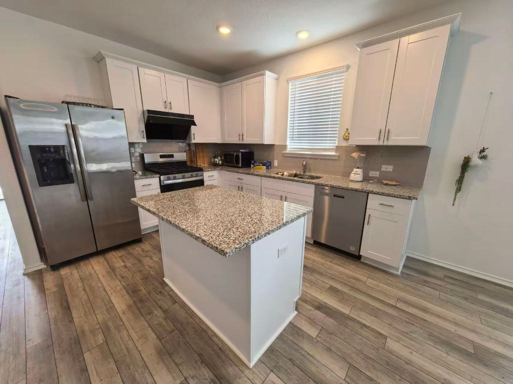 1521 Hope Rnch Road Leander, TX 78641 - Photo 8 of 15 Kitchen featuring stainless steel appliances, white cabinets, light stone countertops, a kitchen island, and recessed lighting