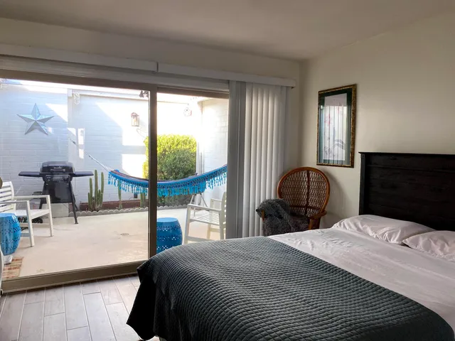 a bedroom with a bed a balcony and large windows