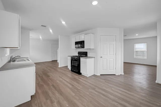 a kitchen with stainless steel appliances a stove a microwave and a hard wood floors