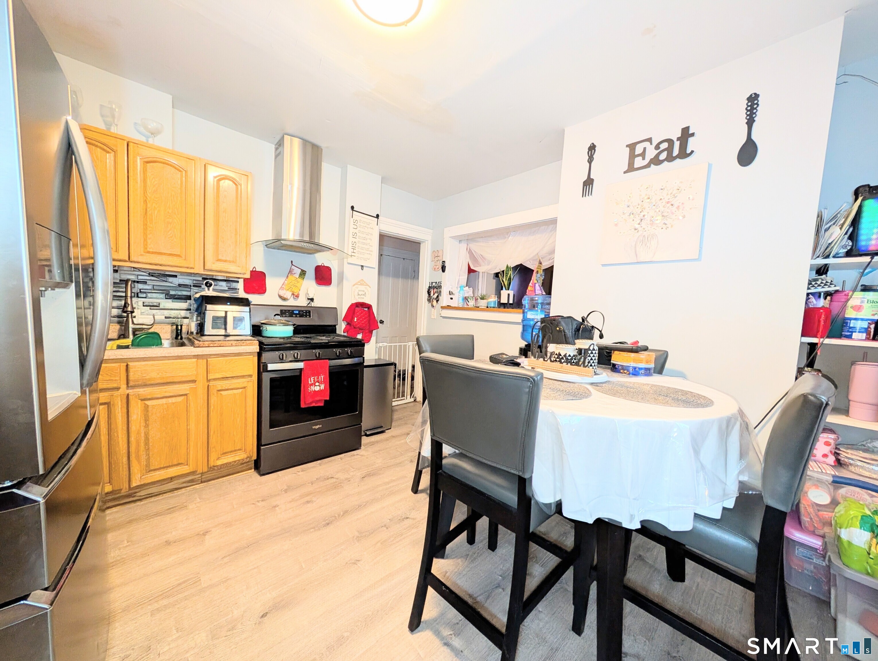188 Holly Street Bridgeport, CT 06607 - Photo 13 of 33 a kitchen with a stove a refrigerator and a dining table with wooden floor