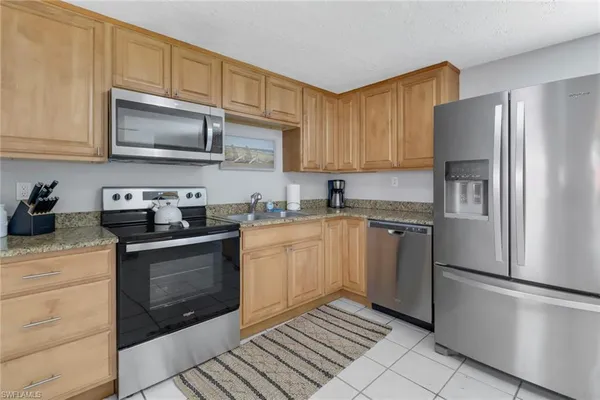 a kitchen with granite countertop a refrigerator stove and microwave