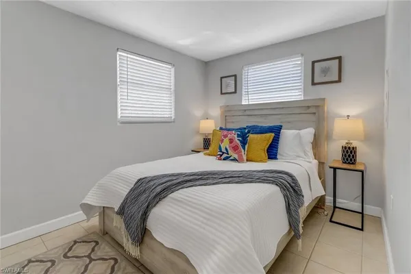 a bed sitting in a bedroom next to a window with a lamp