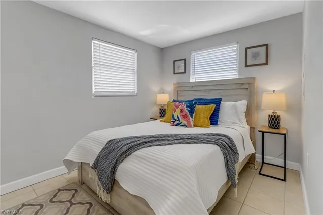 a bed sitting in a bedroom next to a window with a lamp