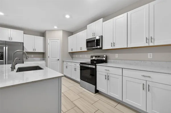 a kitchen with granite countertop white cabinets white stainless steel appliances and sink