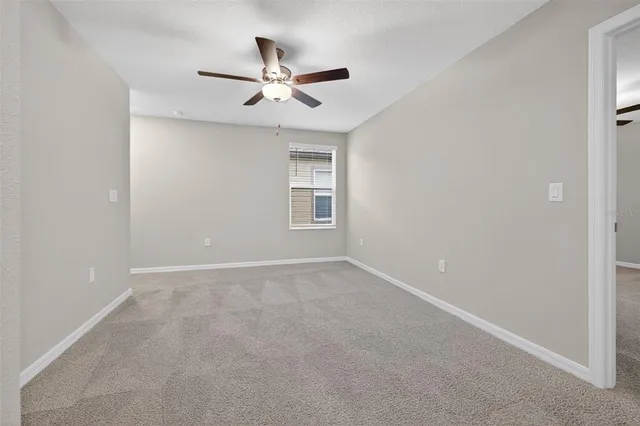 an empty room with windows and ceiling fan