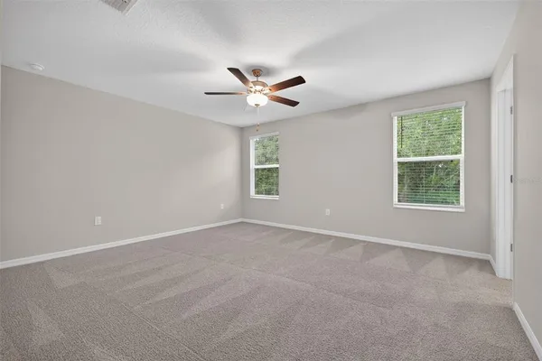 an empty room with a window and a fan