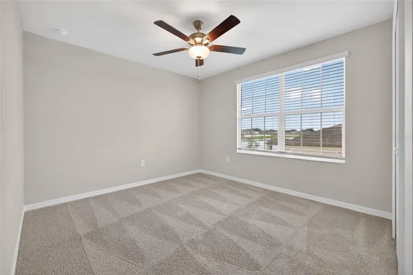 an empty room with ceiling fan and windows
