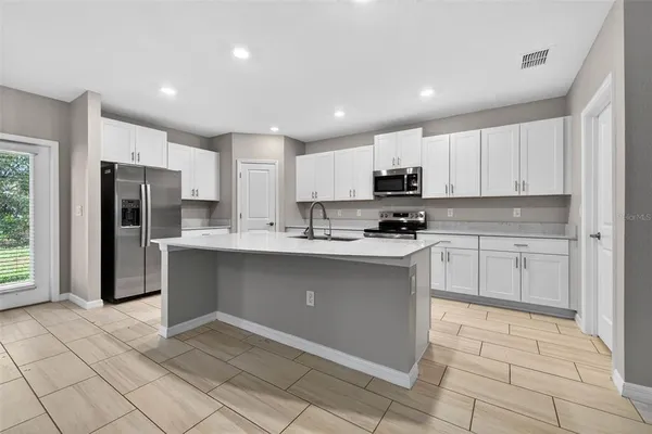 a kitchen with granite countertop a refrigerator and a stove top oven