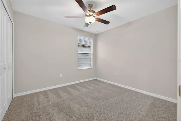 an empty room with windows and ceiling fan