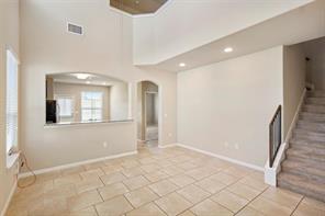 407 Epiphany Lane Pflugerville, TX 78660 - Photo 25 of 29 Unfurnished living room with arched walkways, a high ceiling, recessed lighting, and light tile patterned floors