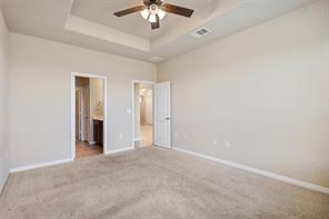407 Epiphany Lane Pflugerville, TX 78660 - Photo 9 of 29 Unfurnished bedroom featuring carpet flooring, ceiling fan, connected bathroom, and a raised ceiling