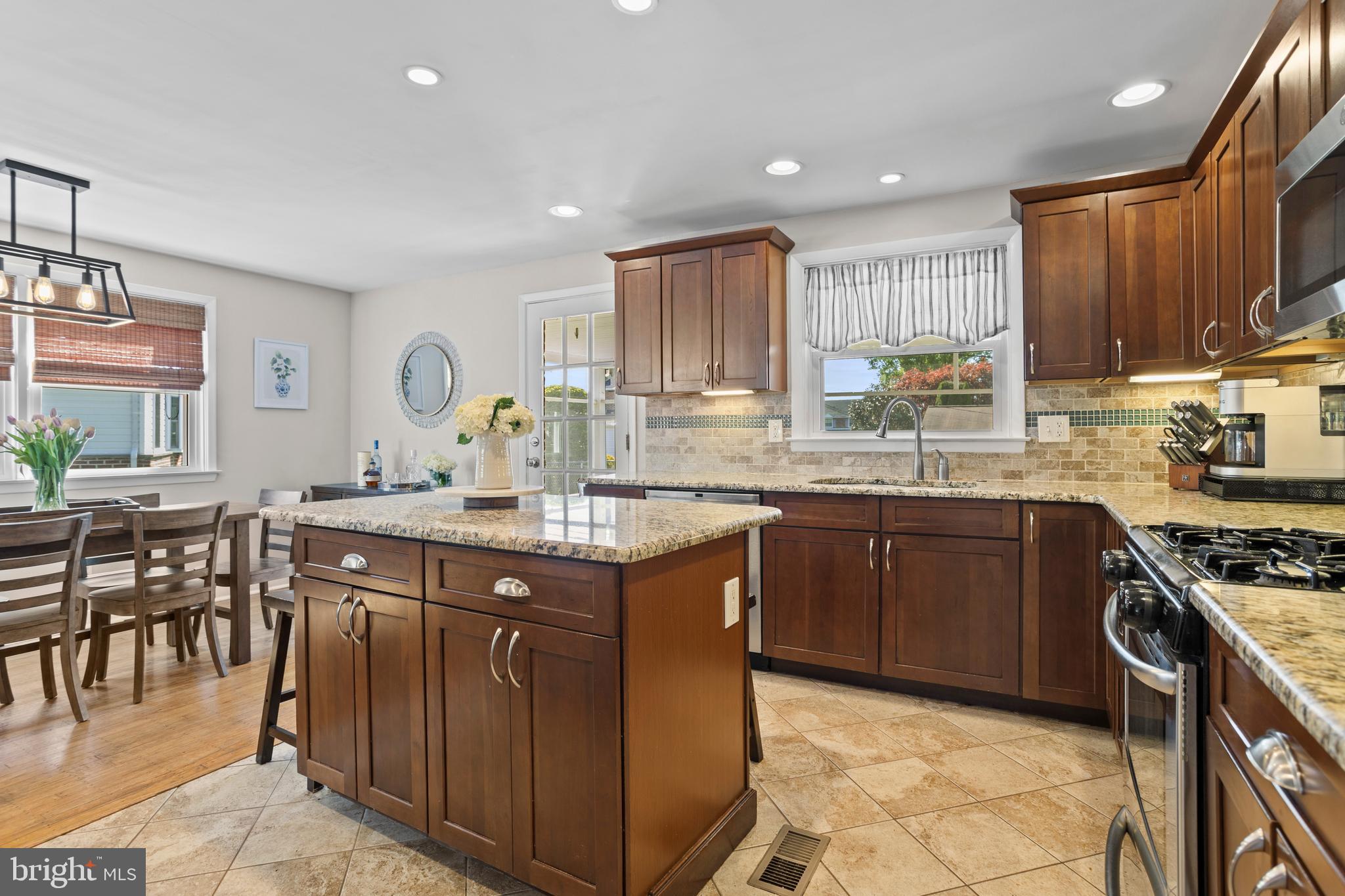105 Longview Drive Springfield, PA 19064 - Photo 13 of 33 a kitchen with stainless steel appliances granite countertop wooden cabinets a sink a stove a dining table and chairs