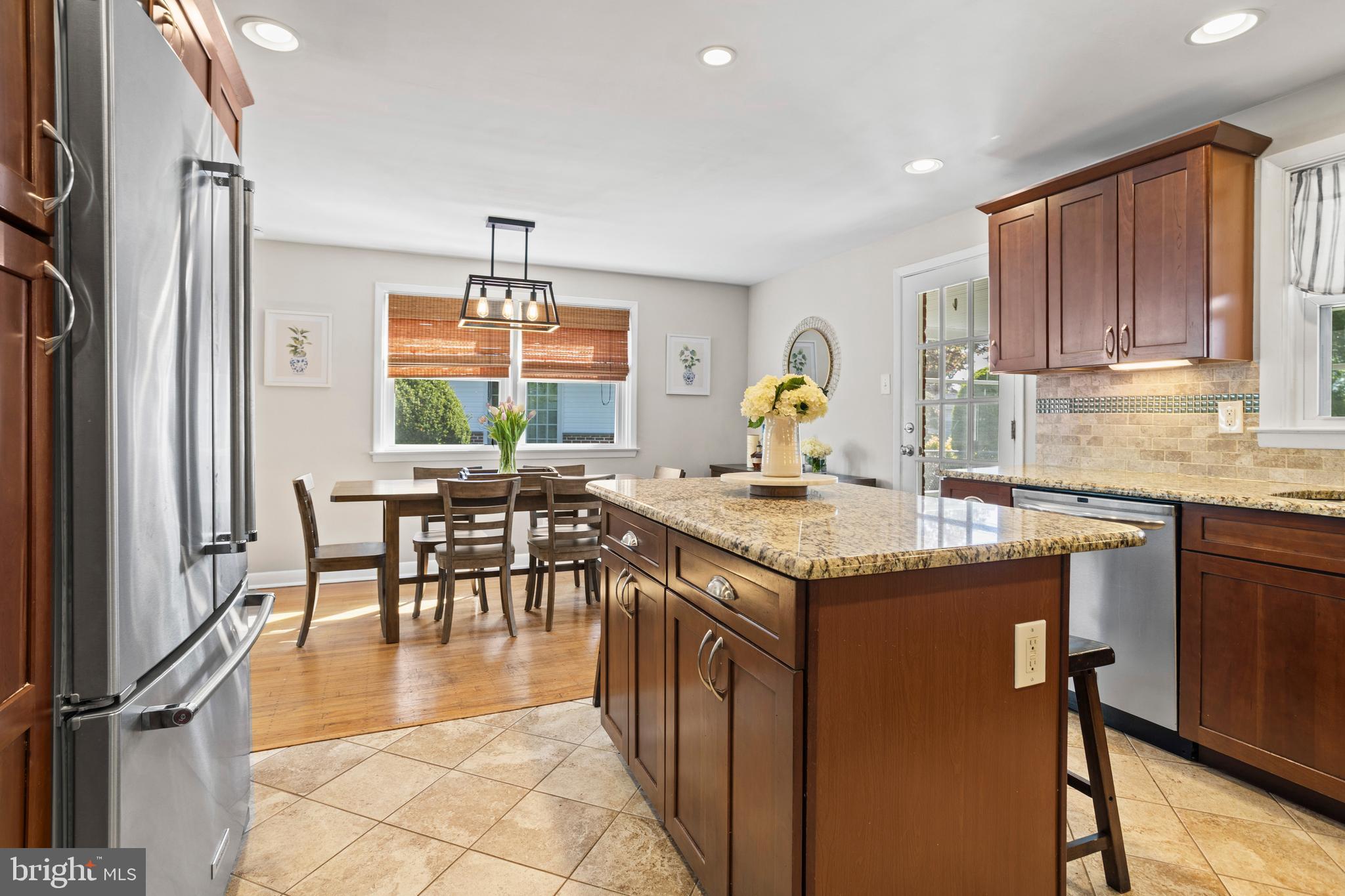 105 Longview Drive Springfield, PA 19064 - Photo 14 of 33 a kitchen with granite countertop a stove a sink a dining table and chairs with wooden floor
