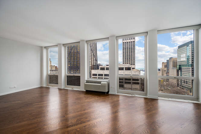 111 East Chestnut Street, Unit 22H Chicago, IL 60611 - Photo 6 of 27 an empty room with wooden floor and windows