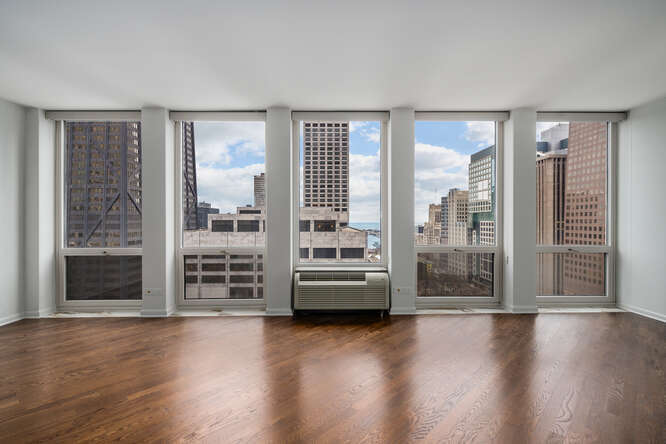 111 East Chestnut Street, Unit 22H Chicago, IL 60611 - Photo 7 of 27 an empty room with wooden floor and windows