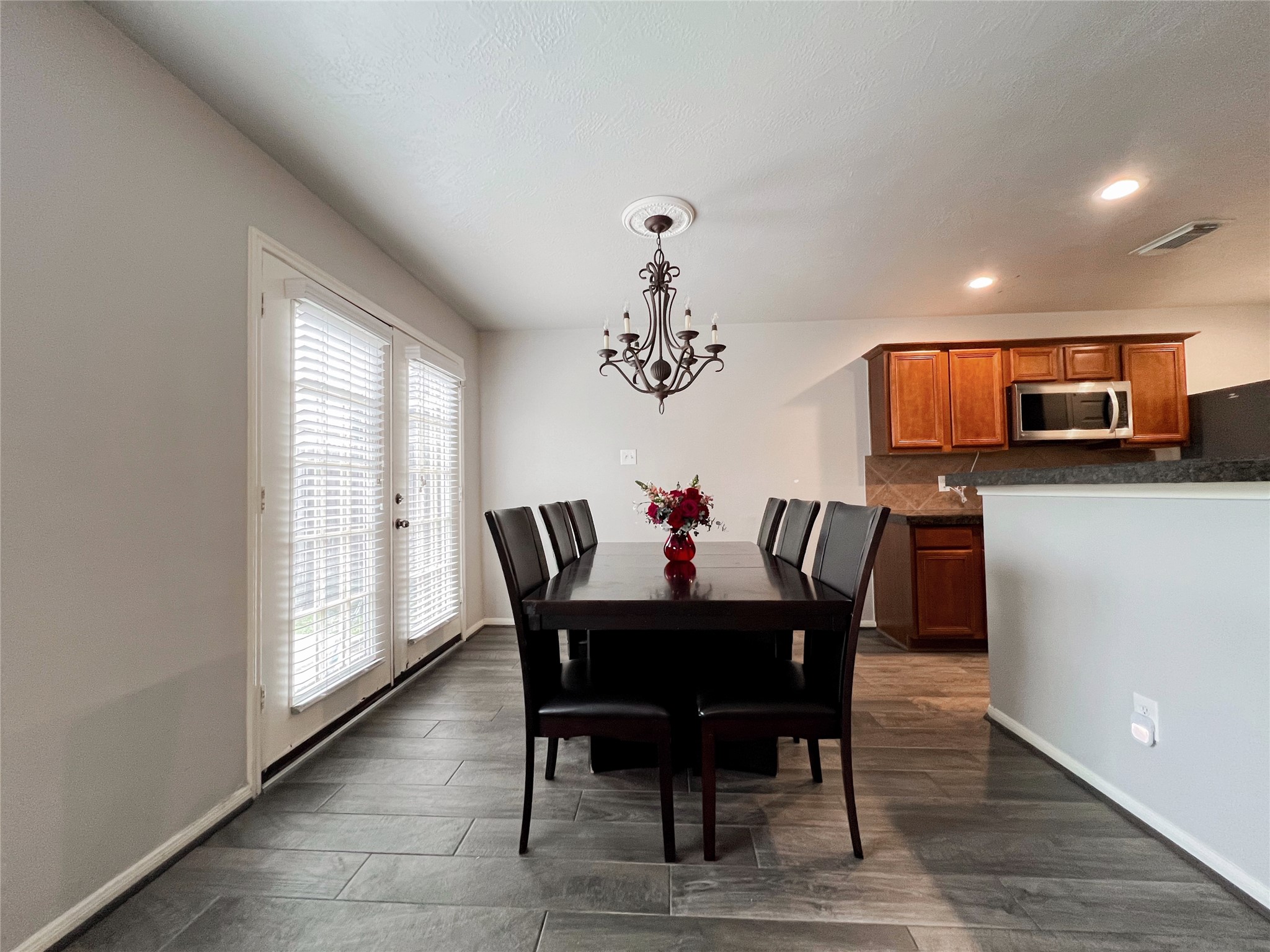 10838 Waterfern Court Houston, TX 77064 - Photo 12 of 28 Spacious dining area with abundant natural light, highlighted by a stylish chandelier and sliding doors leading to the backyard. Perfect for hosting family dinners or intimate gatherings.