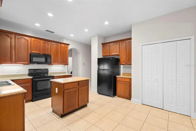 a large kitchen with stainless steel appliances kitchen island granite countertop a refrigerator and a sink