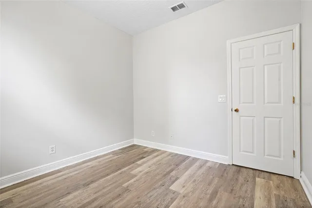 a view of an empty room with wooden floor and a ceiling fan