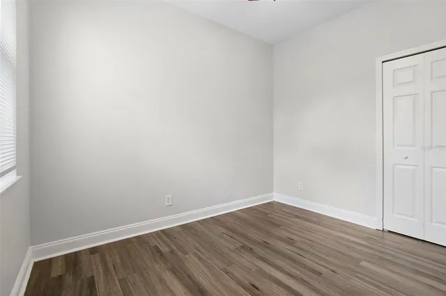 an empty room with wooden floor ceiling fan and windows