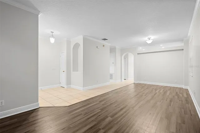 a view of an empty room with wooden floor and windows