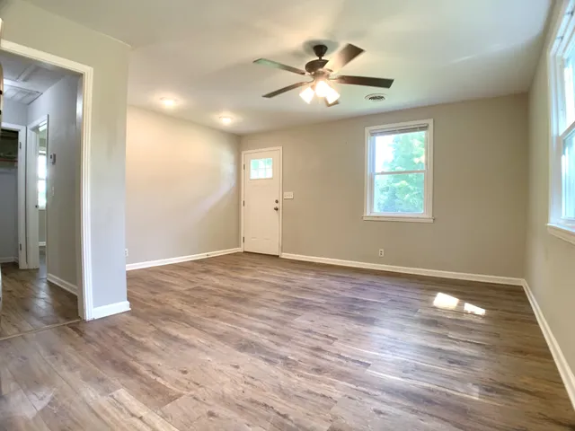 an empty room with wooden floor and windows
