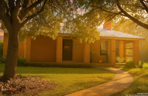 a view of yellow house with a large tree