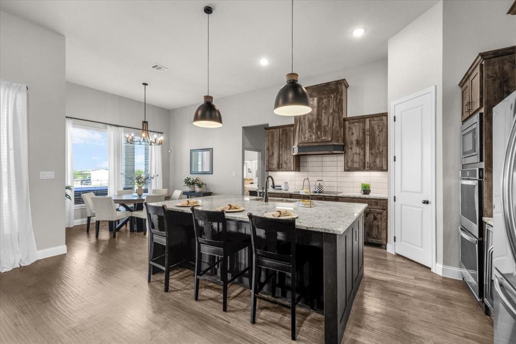 329 Palo Alto Drive Springtown, TX 76082 - Photo 10 of 34 Central kitchen island with a light-toned countertop, wood-finish flooring, dark wood cabinetry, and stainless steel appliances