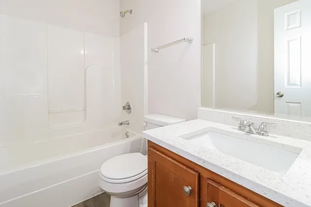 a bathroom with a granite countertop sink a toilet and a bathtub