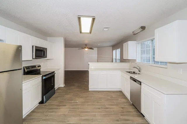 a kitchen with a sink a stove top oven and white stainless steel appliances