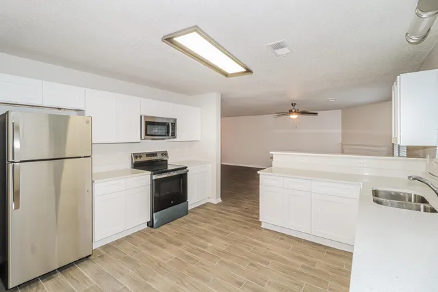 a kitchen with granite countertop a refrigerator stove top oven and sink