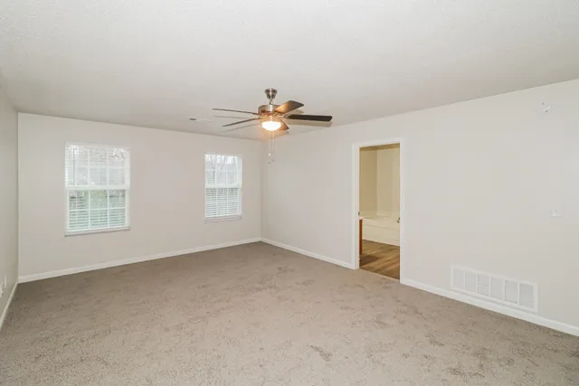 an empty room with windows and fan
