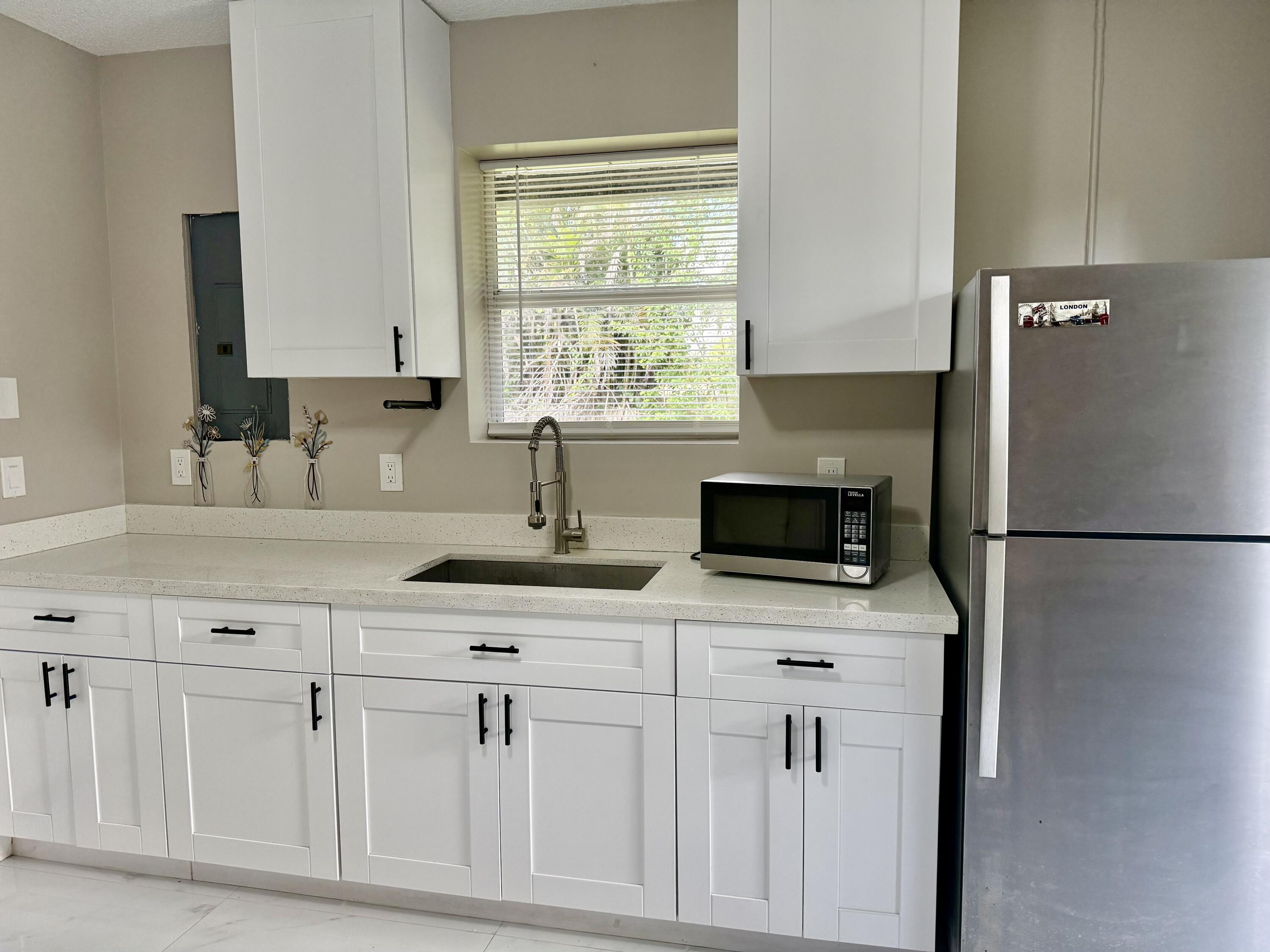 14523 Flamingo Road Loxahatchee Groves, FL 33470 - Photo 46 of 50 a kitchen with white cabinets and a refrigerator