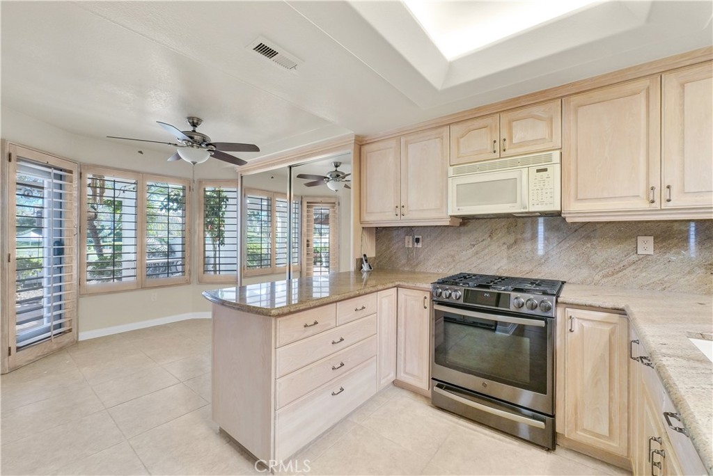 4729 Majorca Way Oceanside, CA 92056 - Photo 10 of 32 a kitchen with granite countertop a stove a sink and dishwasher with white cabinets