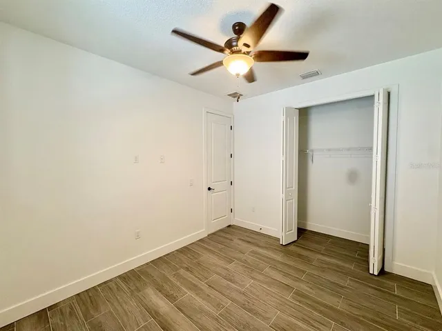 an empty room with wooden floor and a ceiling fan