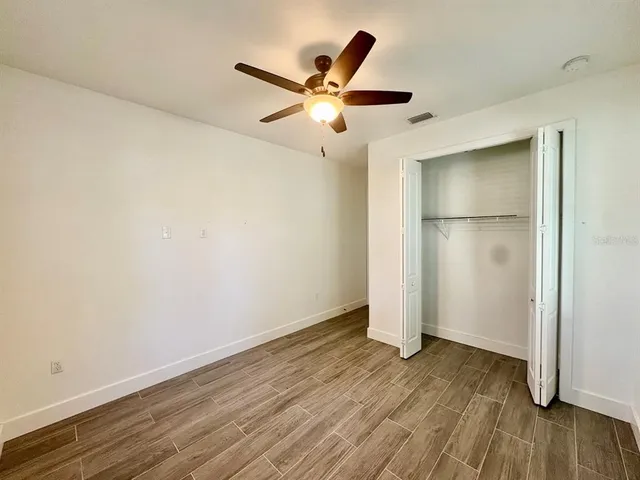 an empty room with wooden floor and a ceiling fan