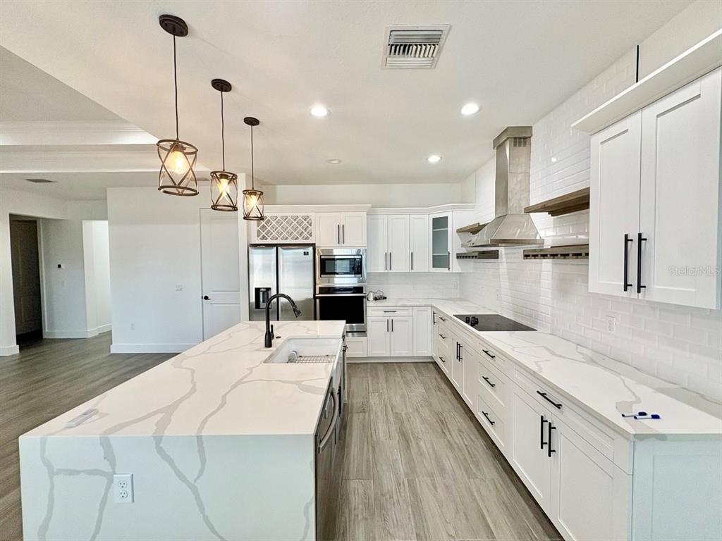 3228 West Beach Street Tampa, FL 33607 - Photo 5 of 22 a large kitchen with kitchen island a stove a sink a refrigerator and a wooden floor