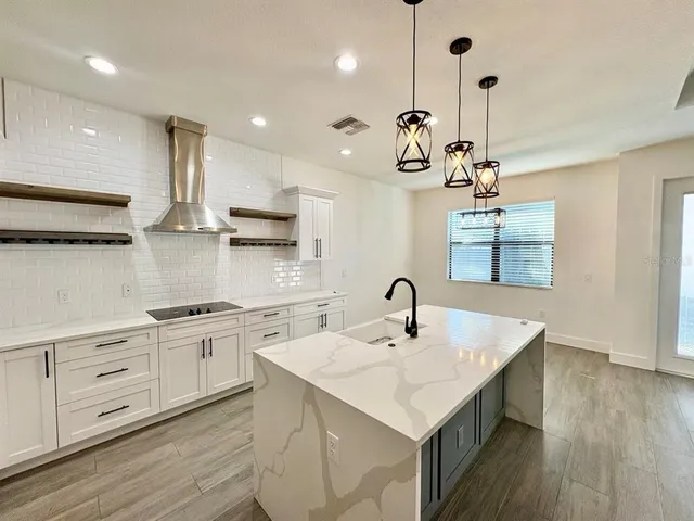 a kitchen with a sink chandelier and wooden floor