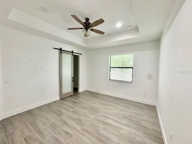 an empty room with wooden floor fan and windows