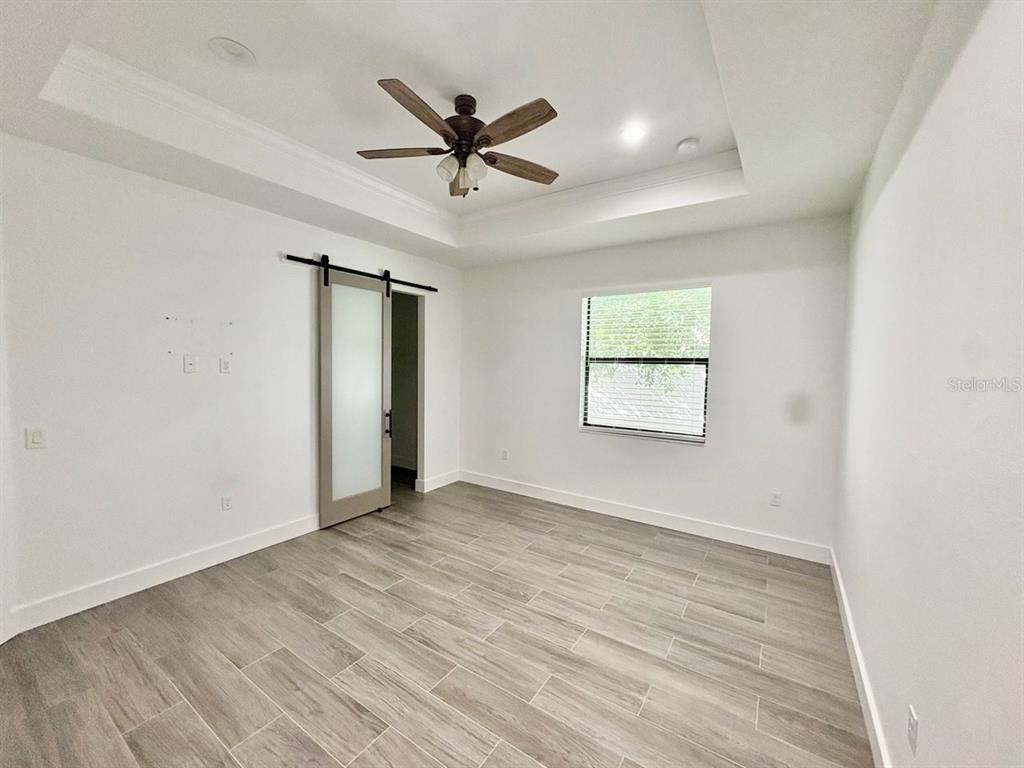 3228 West Beach Street Tampa, FL 33607 - Photo 9 of 22 an empty room with wooden floor fan and windows