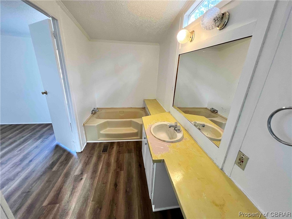 1295 Kates Neck Road Locust Hill, VA 23092 - Photo 20 of 24 Bathroom featuring a bathtub, a textured ceiling, oversized vanity, and wood-type flooring