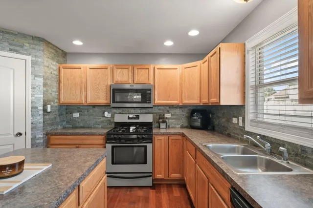 a kitchen with granite countertop a sink a counter top space appliances and cabinets