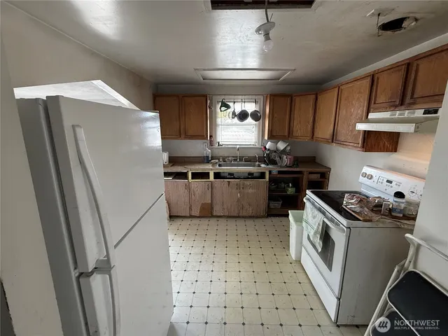 a kitchen with stainless steel appliances granite countertop a stove a sink dishwasher a refrigerator and cabinets with wooden floor