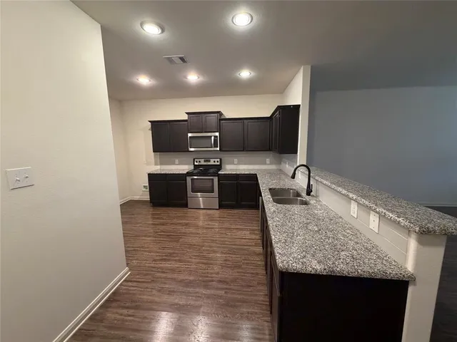 a large kitchen with granite countertop a sink and stainless steel appliances