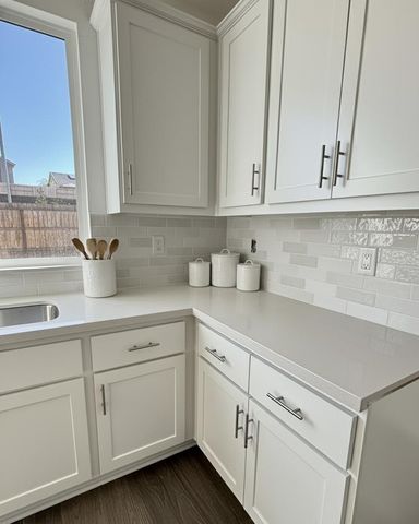 a kitchen with white cabinets and sink