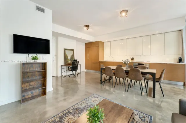 a view of dining room and livingroom with furniture wooden floor a rug a painting and a chandelier