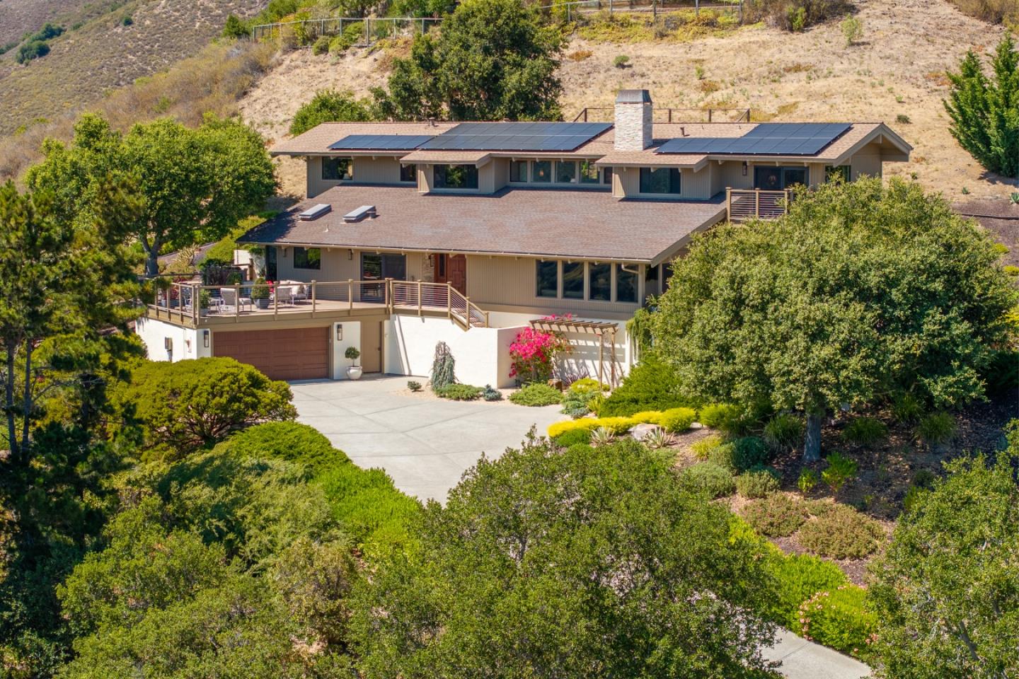 a aerial view of a house with a yard and table and chairs under an umbrella
