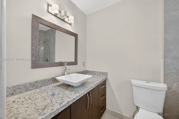 a bathroom with a granite countertop sink and a mirror