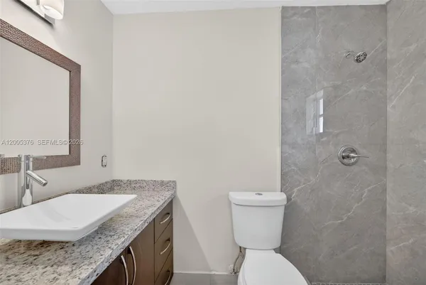 a bathroom with a granite countertop toilet sink and mirror