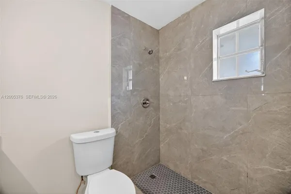 a white toilet sitting next to a shower